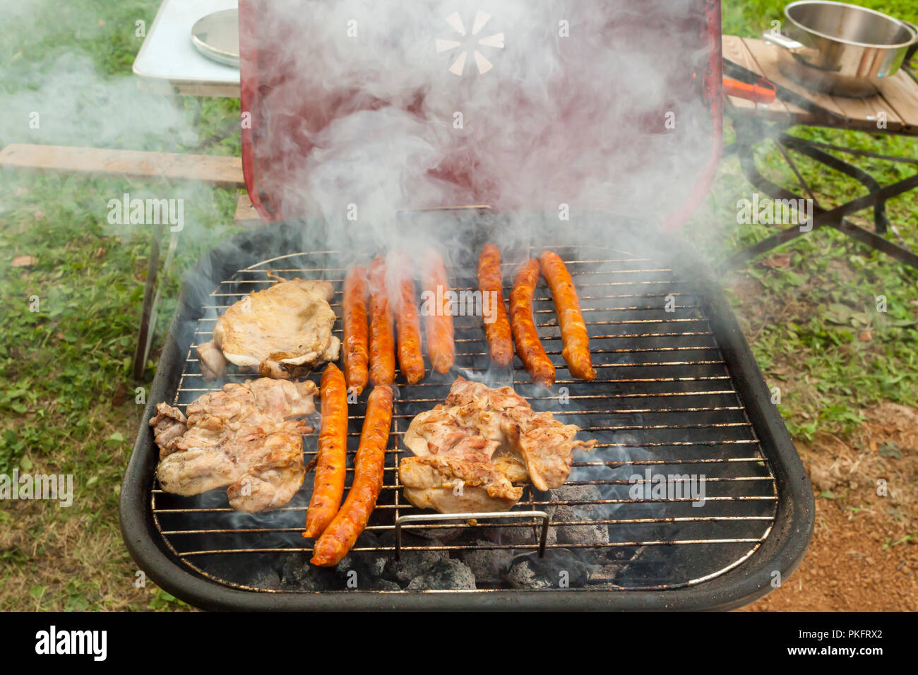 Variety of meat on an outdoor, sunlit, smoking barbecue grill Stock Photo