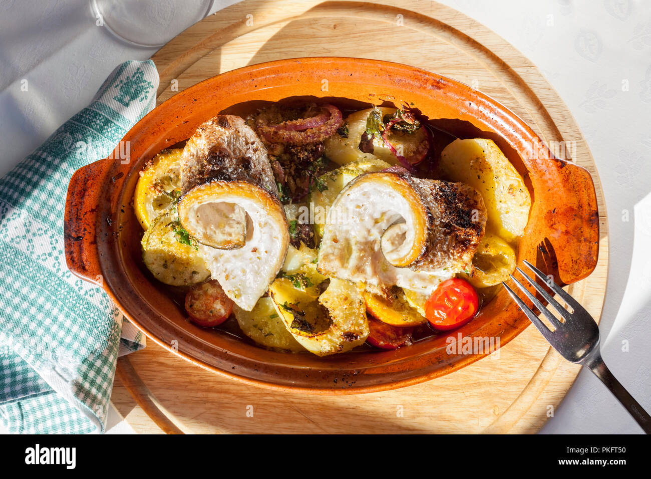 Fish fillet roasted with potatoes, cherry tomato, onion - top view Stock Photo