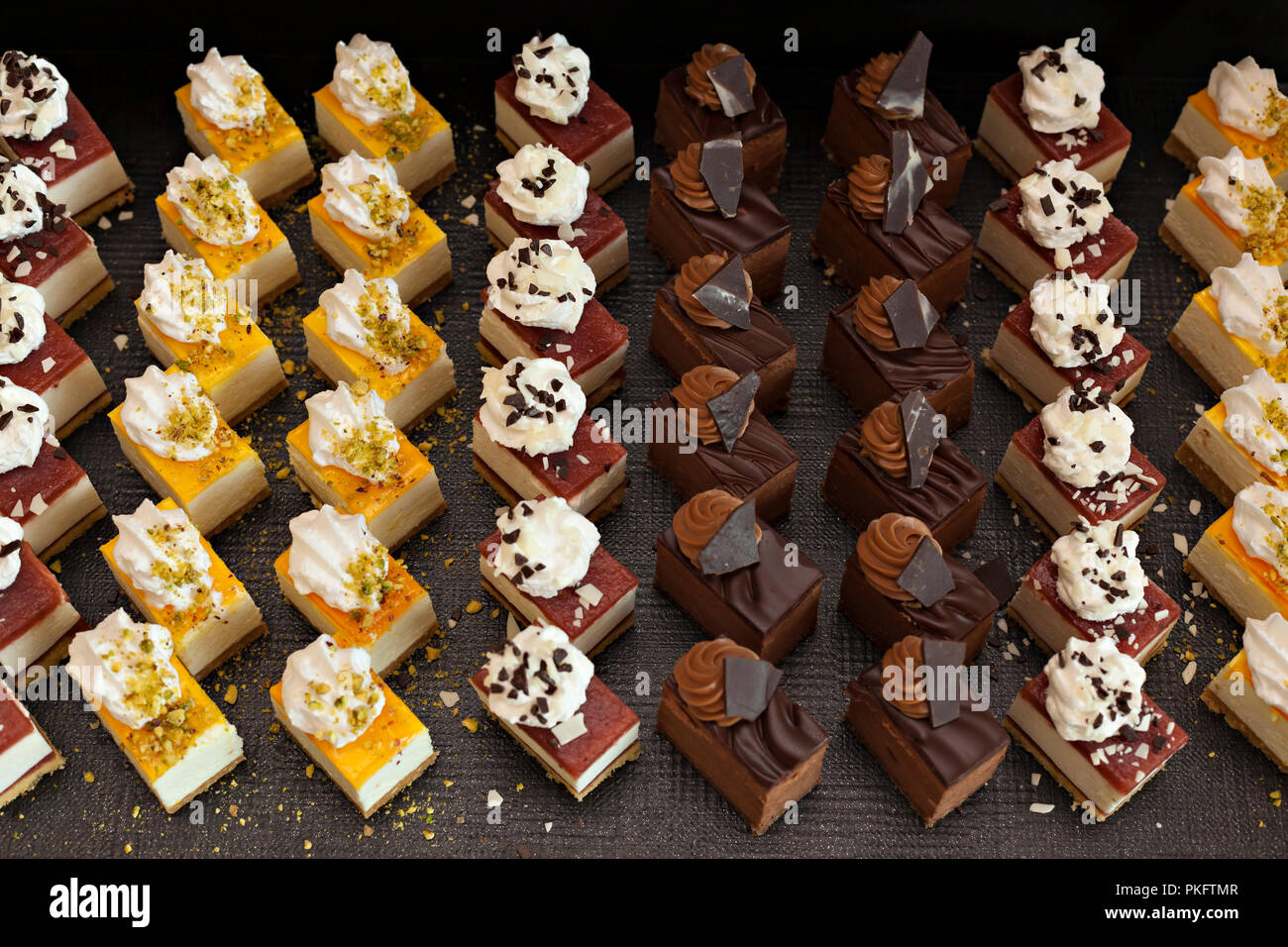 Small chocolate and vanilla layered cakes in rows on candy buffet. Sweet paradise. Stock Photo