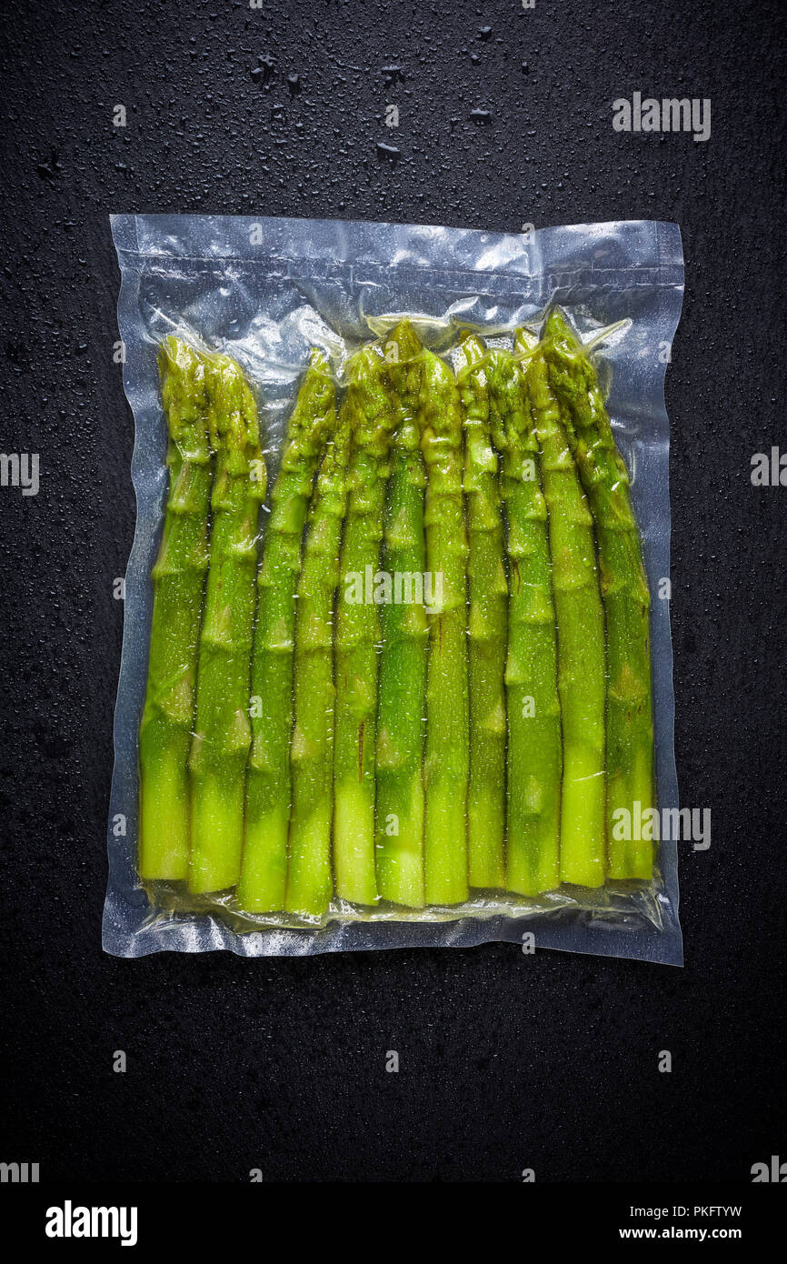 Fresh asparagus vacuum sealed ready for sous vide cooking, on black