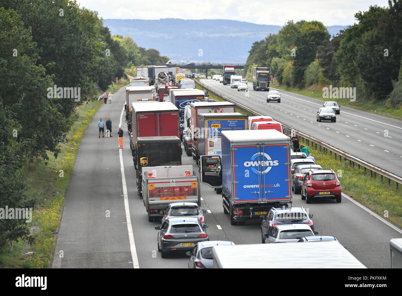 Drivers stand alongside their vehicles on the M5 motorway near Taunton in Somerset after the road was closed following a collision this morning between a lorry and several cars in which two people died. Stock Photo