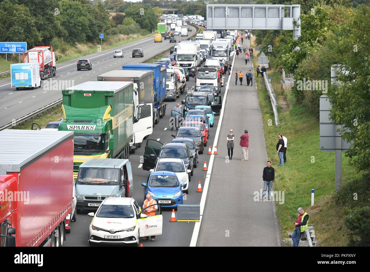 Drivers stand alongside their vehicles on the M5 motorway near Taunton in Somerset after the road was closed following a collision this morning between a lorry and several cars in which two people died. Stock Photo