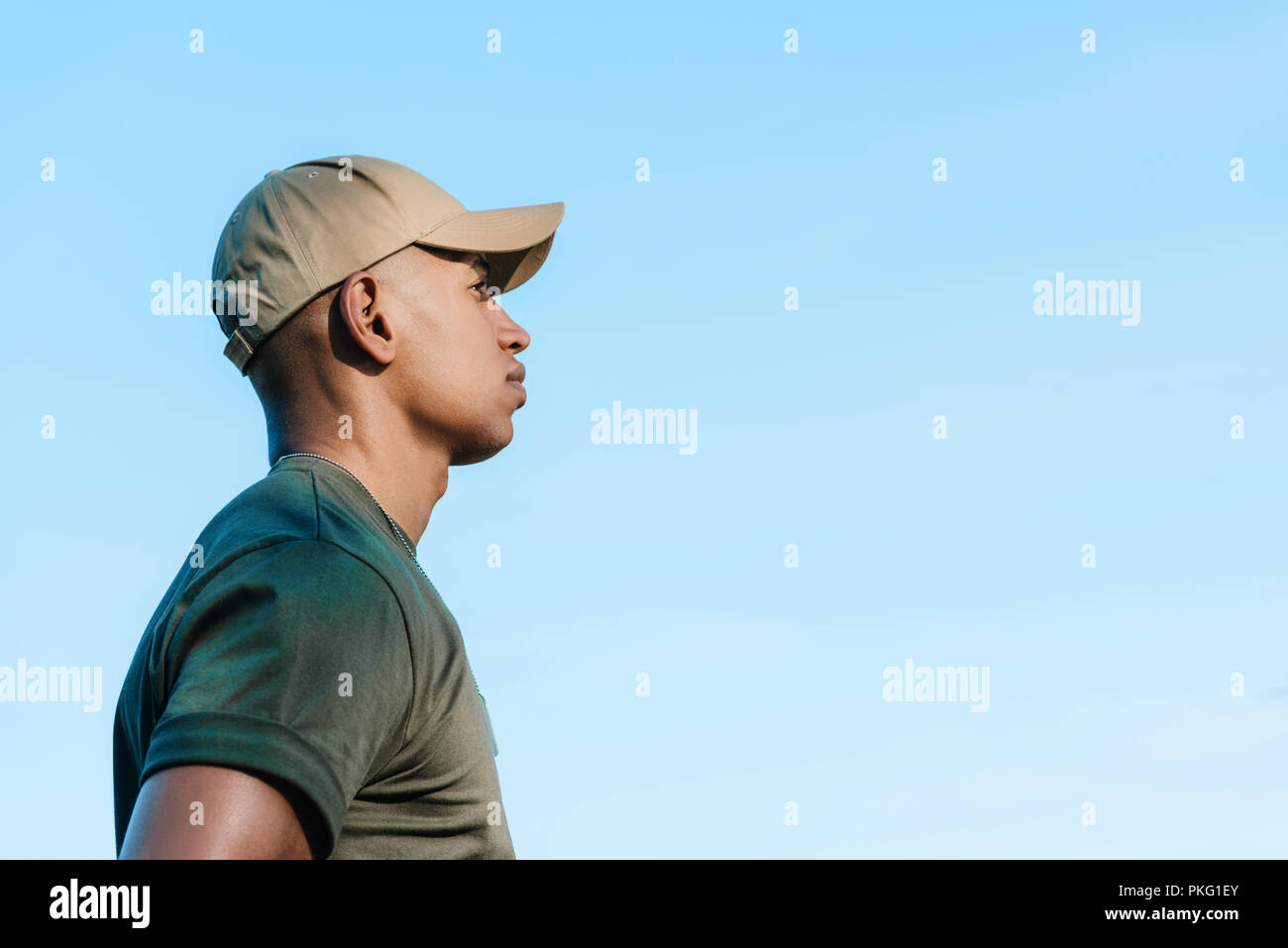 side view of african american soldier in cap against blue sky Stock Photo