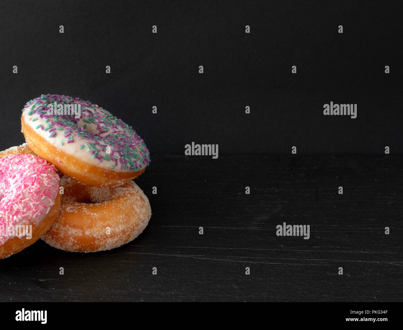 A pile of three ring donuts against a black background Stock Photo