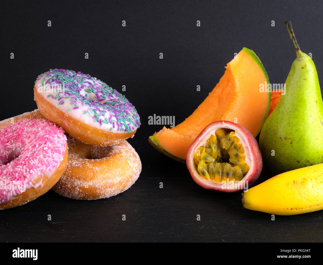 Donuts and fruit showing healthy and unhealthy foods Stock Photo