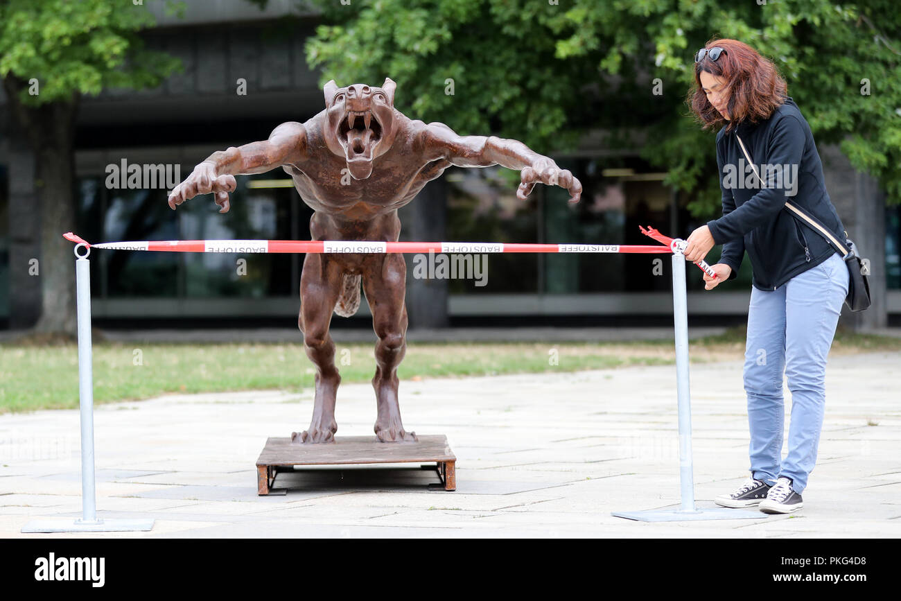 Chemnitz, Saxony. 13th Sep, 2018. A woman locks the bronze statue of an aggressive wolf by the artist Opolka, which symbolizes a hanger, for an art action. With this art action, the artist wants to protest against right-wing hatred and violence. Credit: Jan Woitas/dpa-Zentralbild/dpa/Alamy Live News Stock Photo