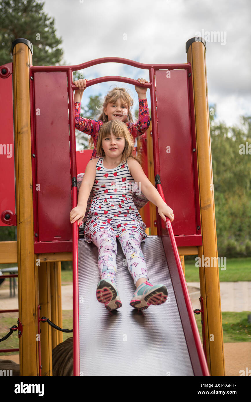 Two Young Girls In A Slide Having Fun And Playing In A Playground Stock