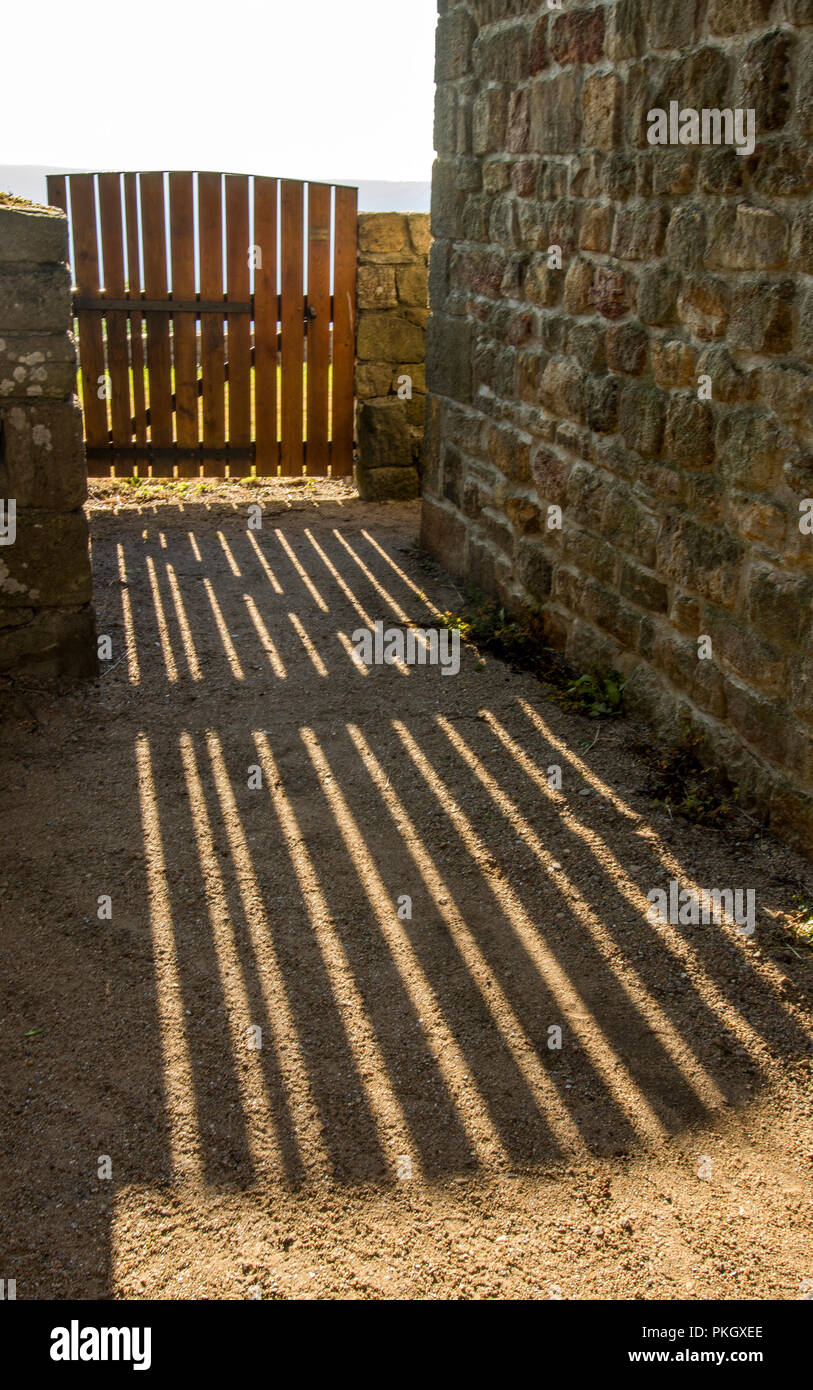 Vertical picture of a wooden fence surrounded by stone buildings under the sunlight Stock Photo