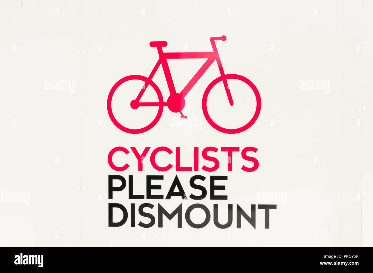 Large red and black sign on white board with picture of bicycle and wording 'cyclists please dismount' in Birmingham city centre Stock Photo