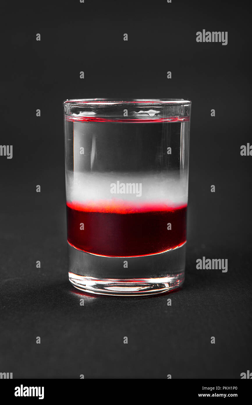 Multicolored layered cocktail, glass with transparent and colored drink