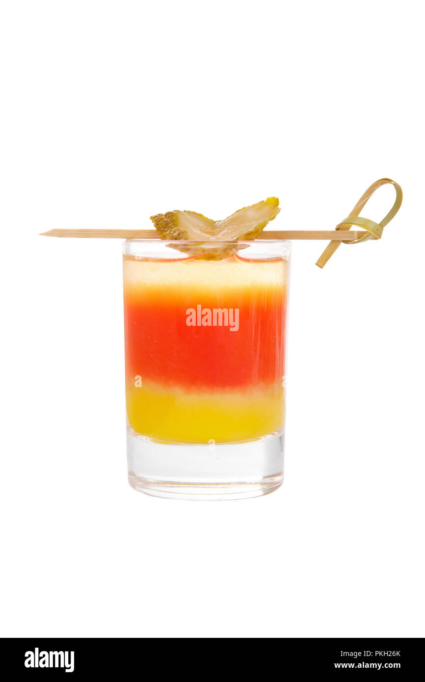 Multicolored layered cocktail, glass with transparent and colored drink, alcoholic, with the taste of tomato, lemon, with skewers salted cucumber, sid Stock Photo