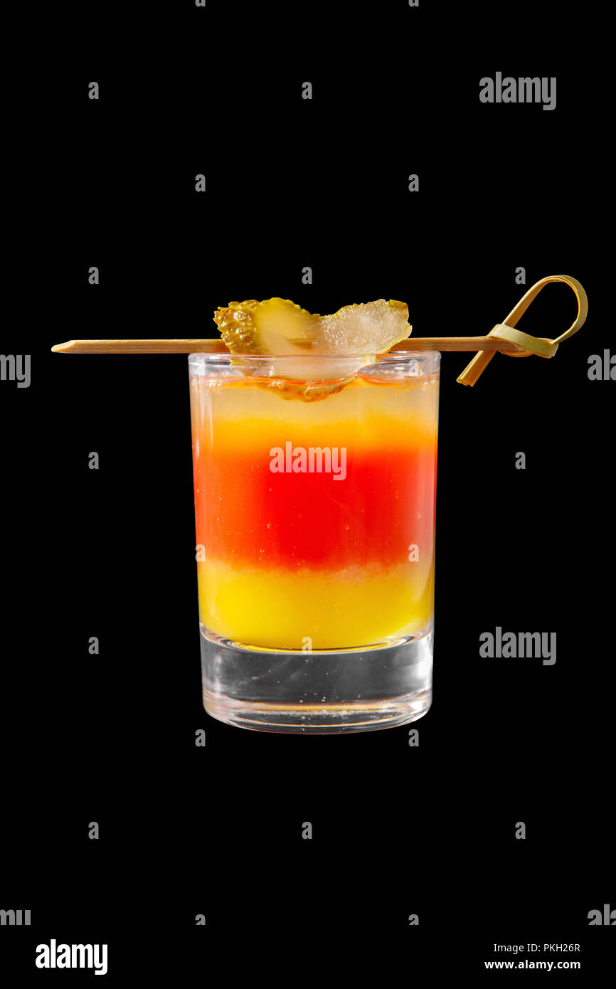 Multicolored layered cocktail, glass with transparent and colored drink, alcoholic, with the taste of tomato, lemon, with skewers salted cucumber, sid Stock Photo