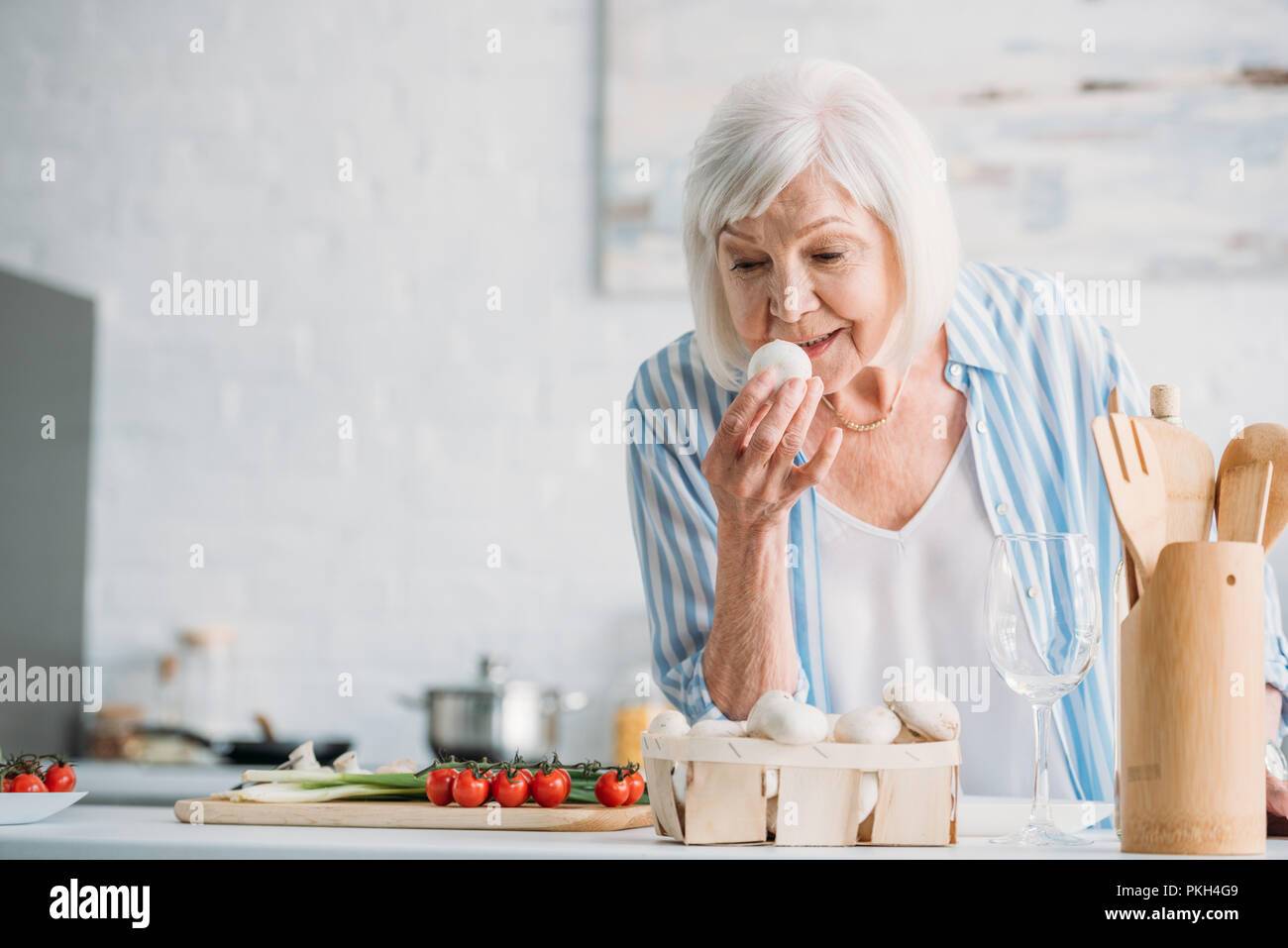 portrait of grey hair lady checking mushrooms while cooking dinner at