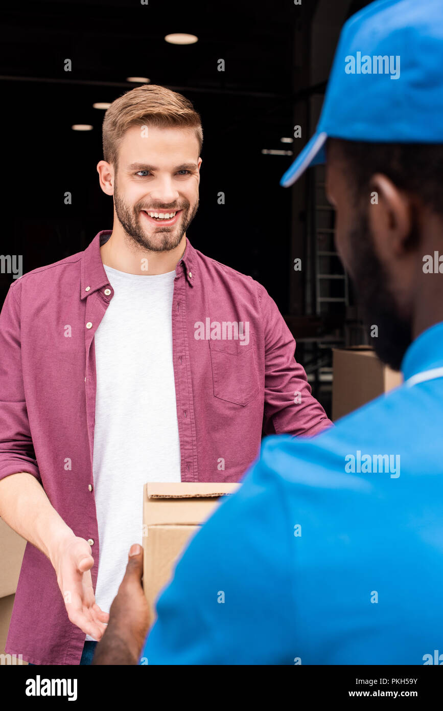 african american courier giving delivery box to smiling customer Stock