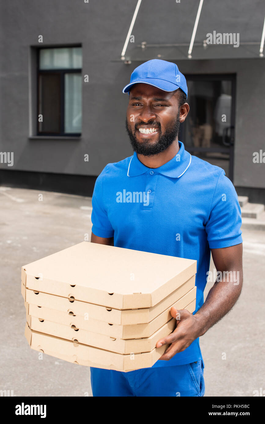 smiling-african-american-delivery-man-holding-pizza-boxes-stock-photo