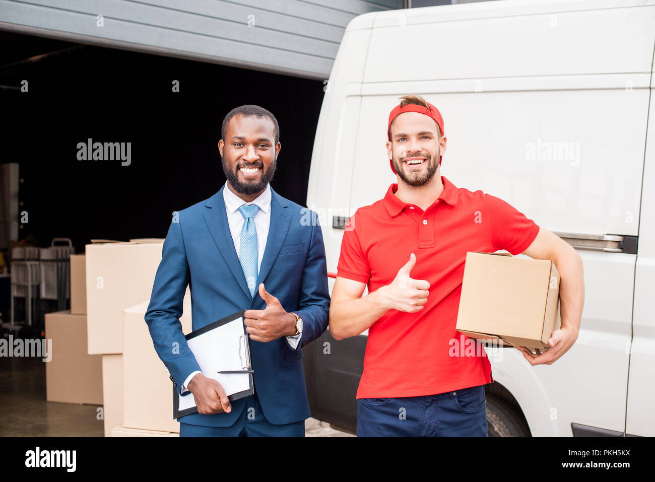 portrait of smiling multicultural client and delivery man showing ...