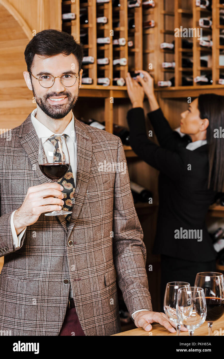 female wine steward taking bottle from shelf for client while he