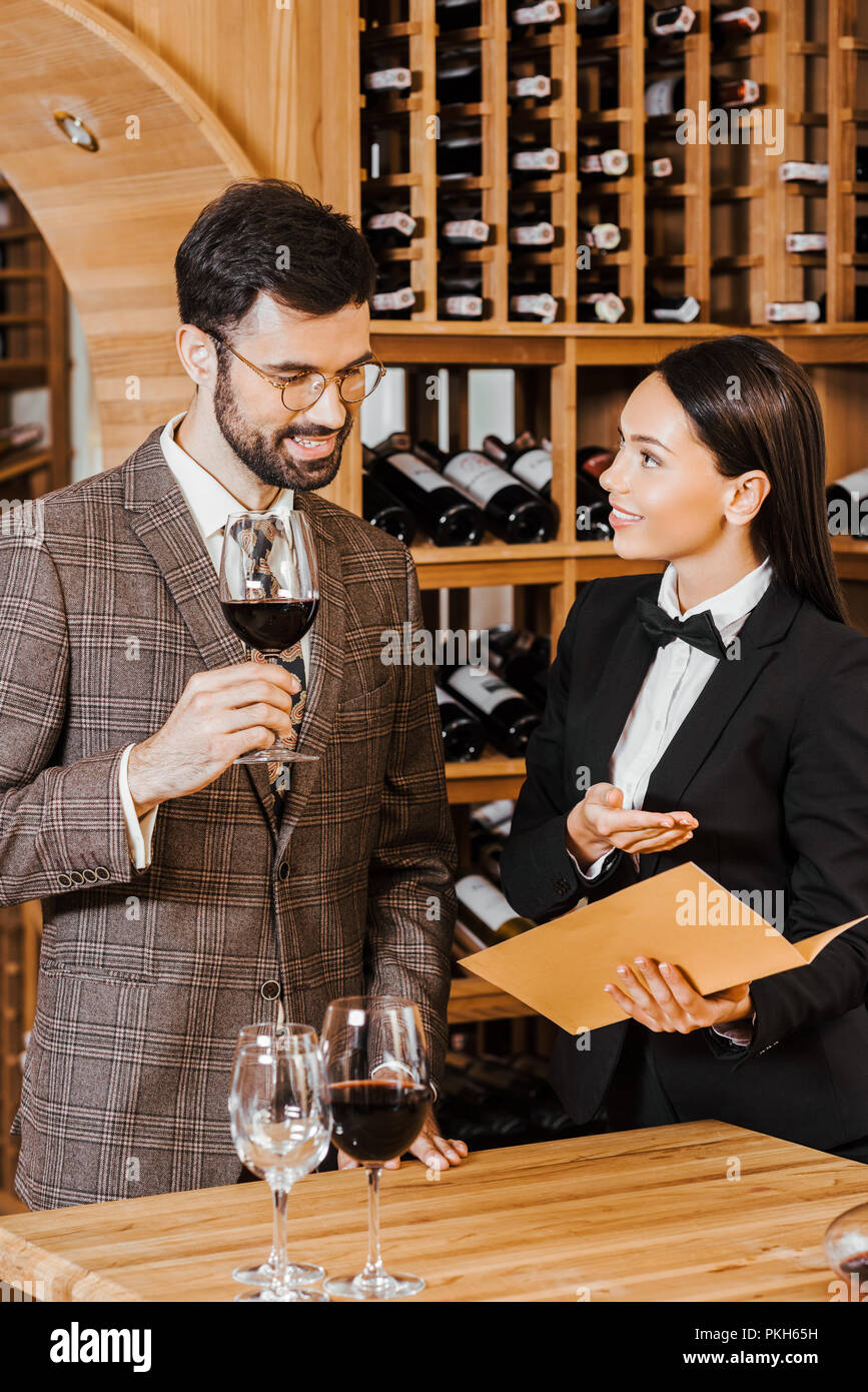 female wine steward showing menu list to client at wine store Stock