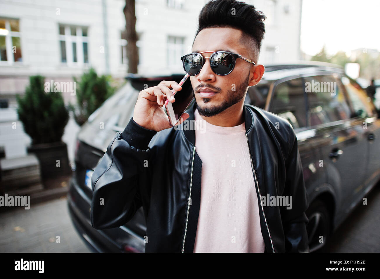Stylish indian beard man at black leather jacket and sunglasses against  business suv car. India model posed outdoor at streets of city and speaking  on Stock Photo - Alamy