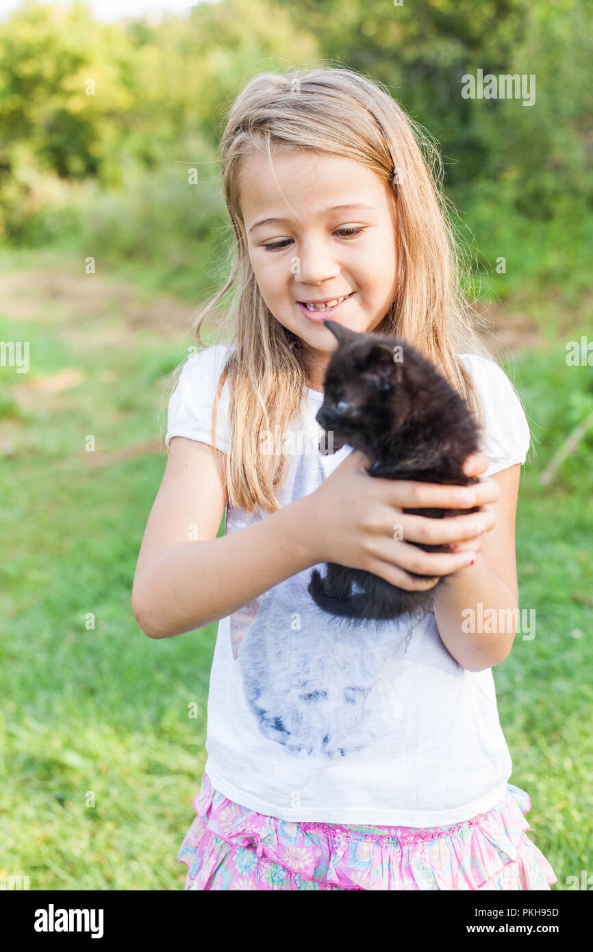 Happy adorable little girl with her domestic kitten outdoors in summer Stock Photo