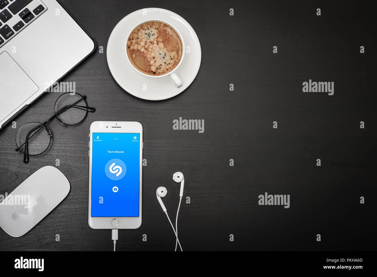 Kyiv, Ukraine - Fabruary 6, 2018: Apple iPhone 8 plus with Shazam app on the screen with headphones and coffee  on black desk, top view. Shazam applic Stock Photo