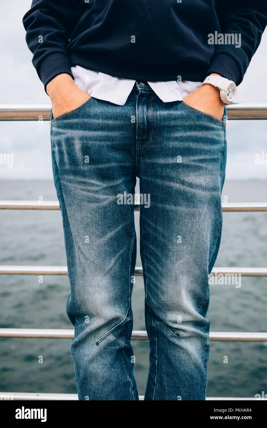 Details of casual clothing in blue and white colors. Lifestyle close-up of fashionable female wearing wristwatches holding hands in pockets of jeans s Stock Photo