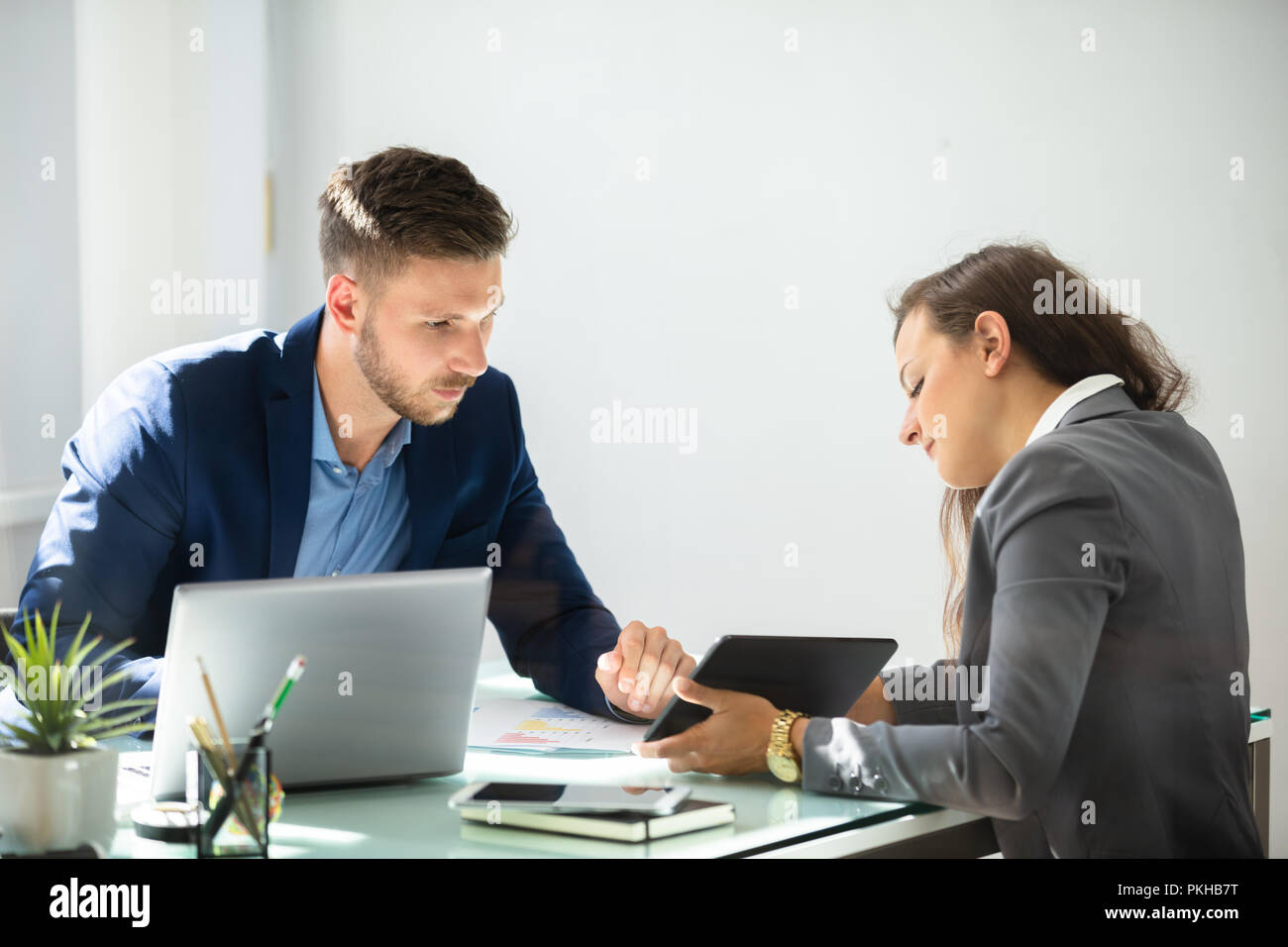 Two Young Businesspeople Using Digital Tablet At Workplace Stock Photo