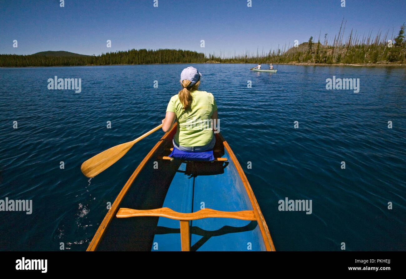 A middle aged married couple paddling a canoe on Waldo Lake, a volcanic caldera lake in the central Oregon Cascades near the town of Oakridge. Stock Photo