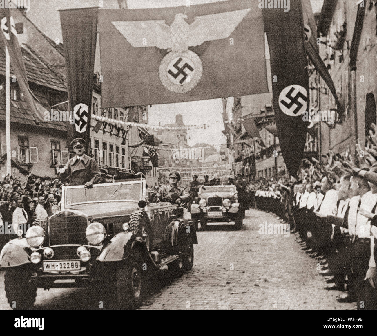 Adolf Hitler, on a victory drive, crossing the frontier from Germany into the Nazi Sudetenland districts of Czechoslovakia, October 3, 1938.   Adolf Hitler,1889 – 1945. German politician, demagogue, Pan-German revolutionary, leader of the Nazi Party, Chancellor of Germany, and Führer of Nazi Germany from 1934 to 1945.   From These Tremendous Years, published 1938. Stock Photo