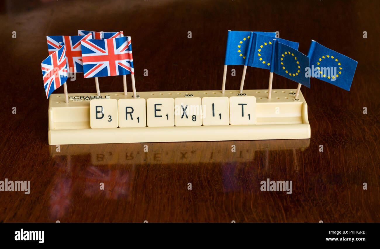 Scrabble letters spelling Brexit in Scrabble tray with Union Jack and EU flags on dark mahogany background Stock Photo