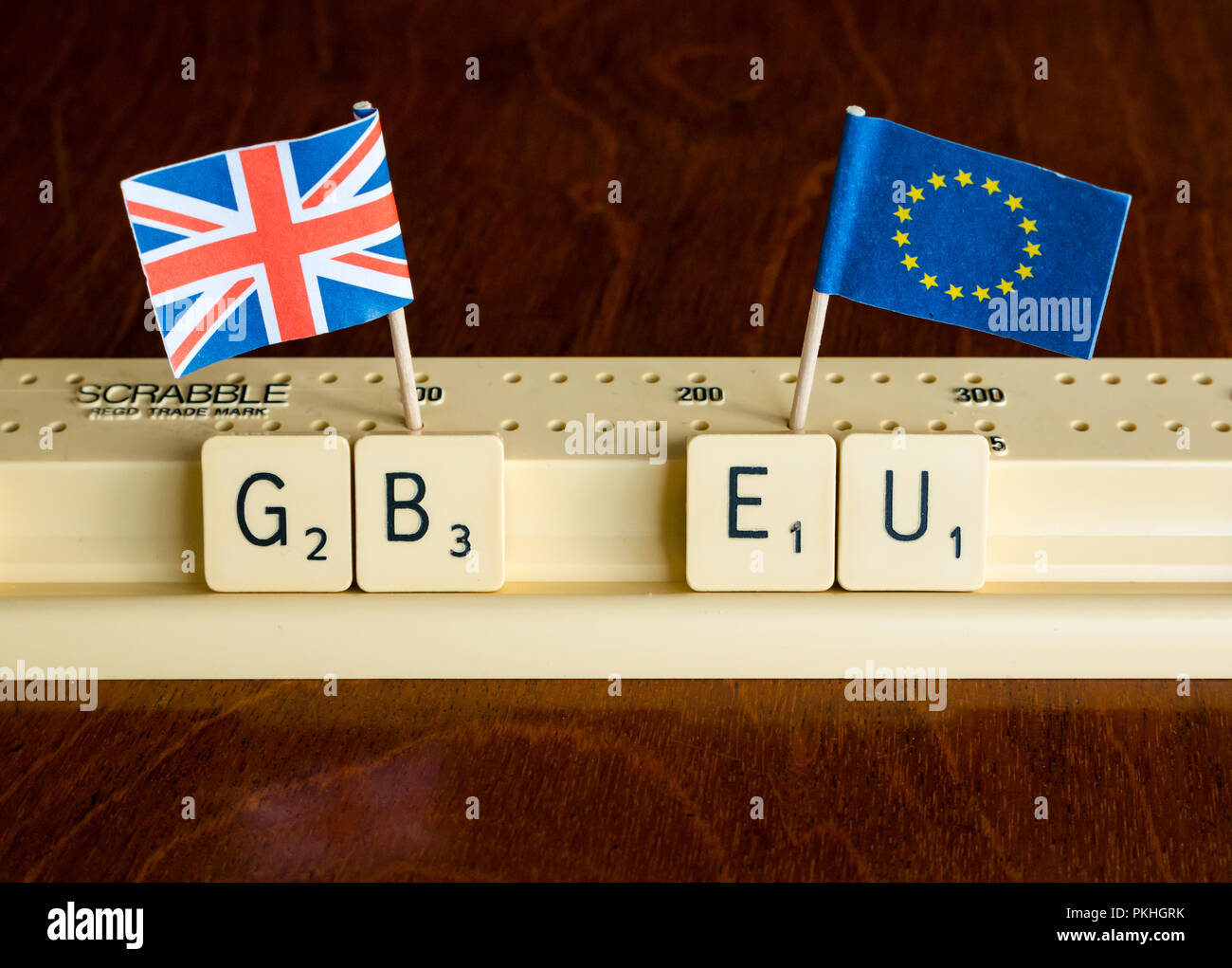 Scrabble letters spelling GB and EU in Scrabble tray with Union Jack and EU flags on dark mahogany background Stock Photo