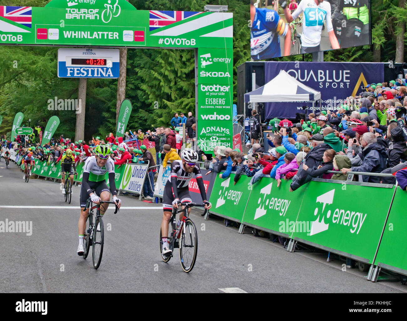 Tour of Britain 2018, Stage 6, 7 September. Tired riders cross the finish line at Whinlatter Visitor Centre in front of large enthusiastic crowds. Stock Photo