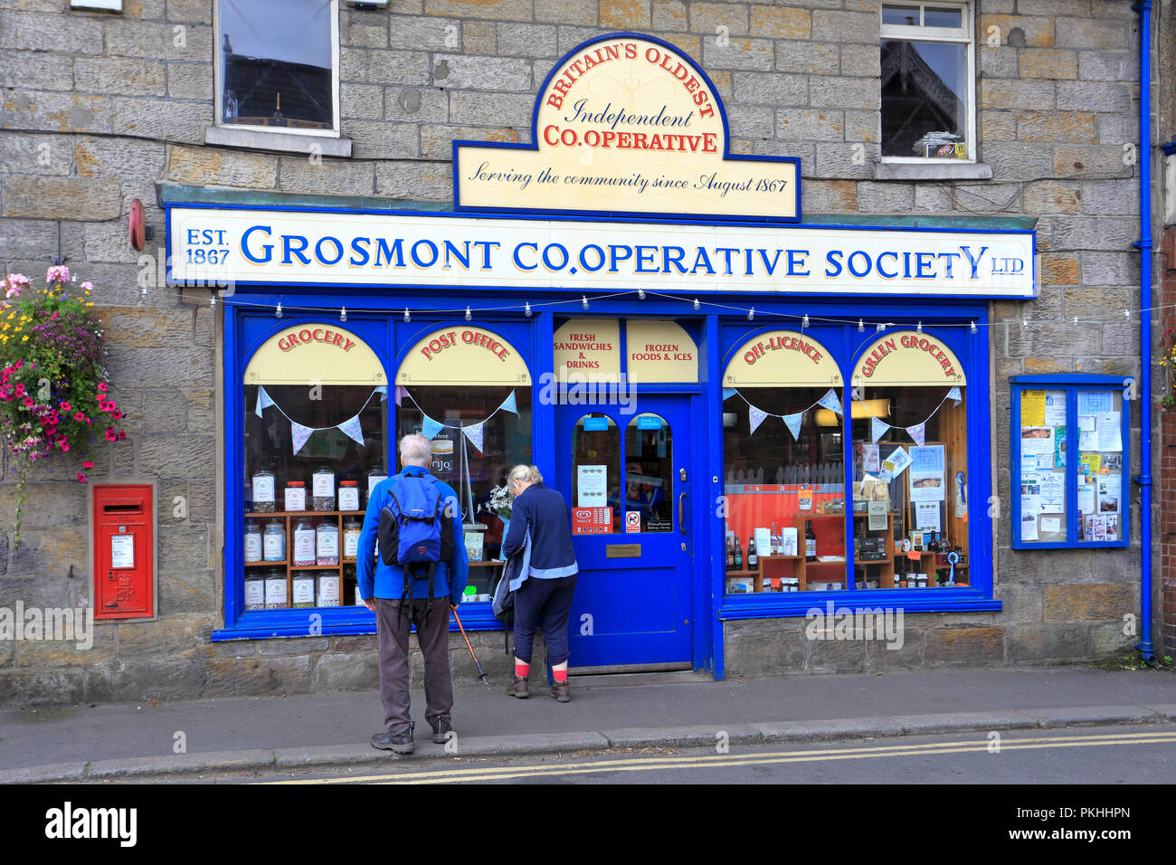 A couple of walkers outside Grosmont Cooperative Society Ltd, Britain's oldest Independent Cooperative, Grosmont, North Yorkshire, England, UK. Stock Photo