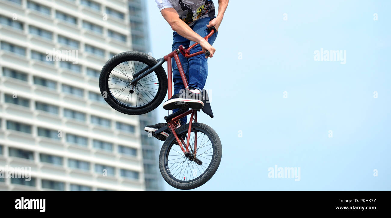 man doing tricks on a BMX bike. freestyle against the backdrop of urban landscape Stock -