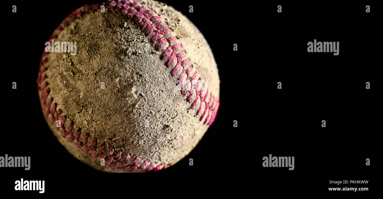 Baseball close up against black background with copy space. Ball is used, rough, dirty, old. Side lighting with sharp focus on texture details. Stock Photo