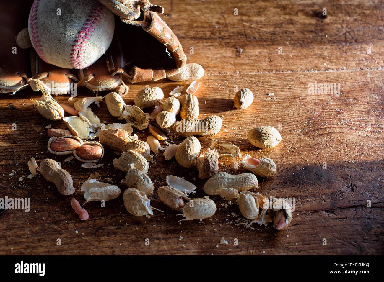 Baseball, glove and ball on rustic wood with scattered peanuts and shells. Theme for America's favorite sport. Vintage look and feel. Copy space. Stock Photo
