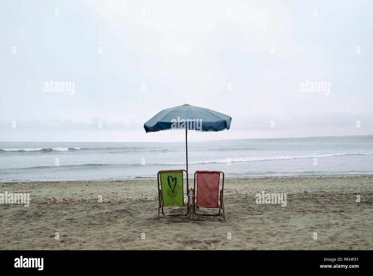 Lonely beach chairs and sun umbrella with ocean view. The wintery landscape of Huanchaco beach, Trujillo region, Peru. Jul 2018 - RF Stock Photo
