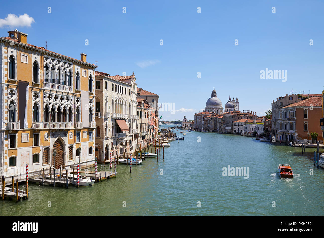 Grand Canal in Venice at midday with Saint Mary of Health basilica and motorboat in Italy Stock Photo