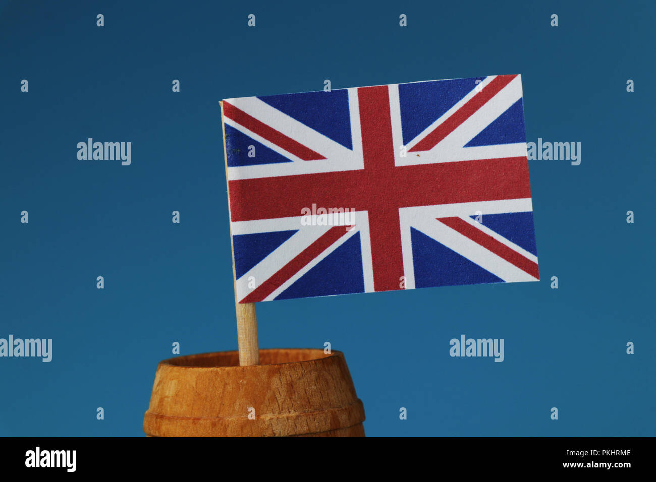 A detail on paper national flag of united kingdom on wooden stick in wooden barrel. Blue background Stock Photo