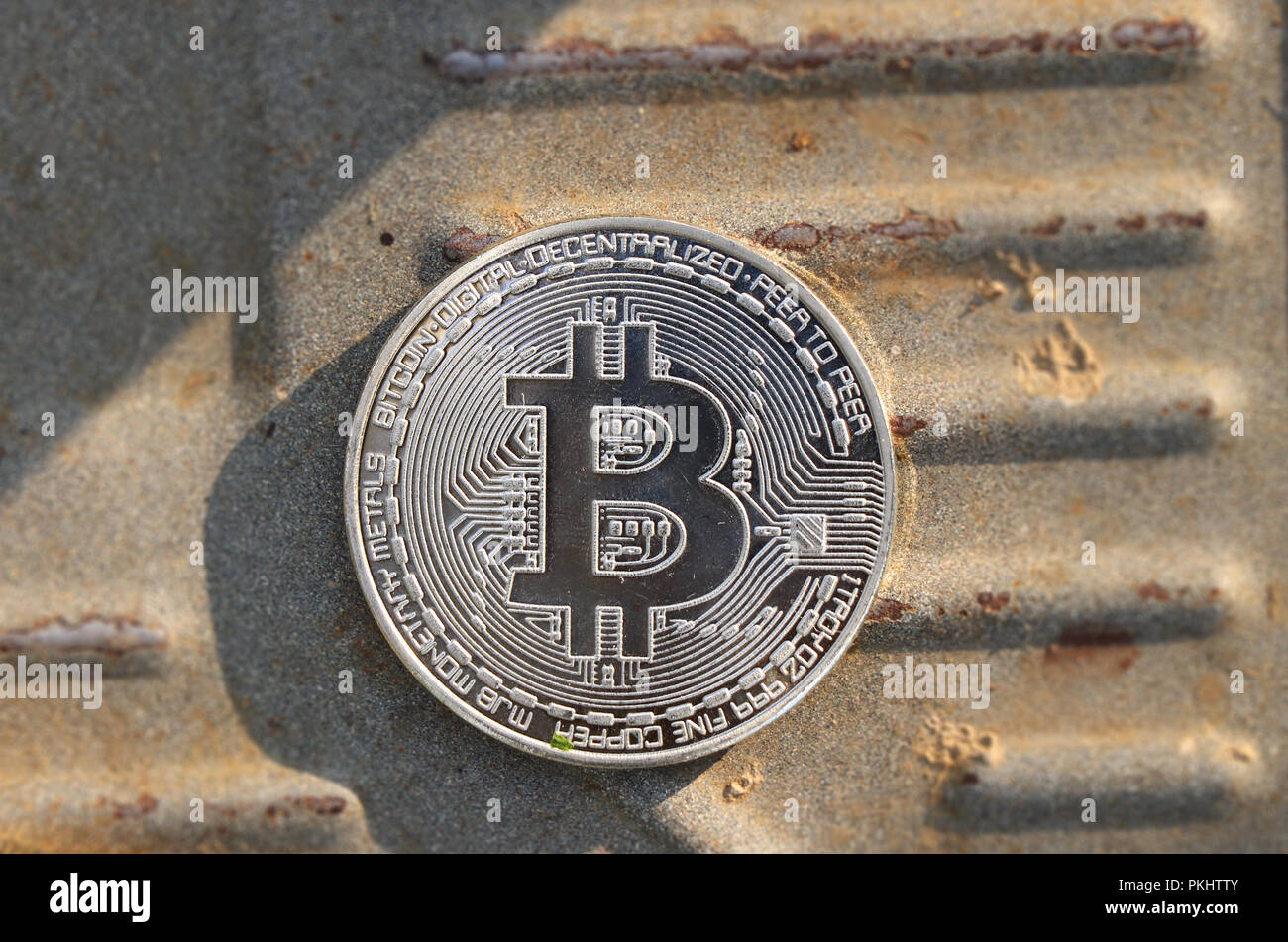 A one silver bitcoin in the middle of iron board. New currency in the ...