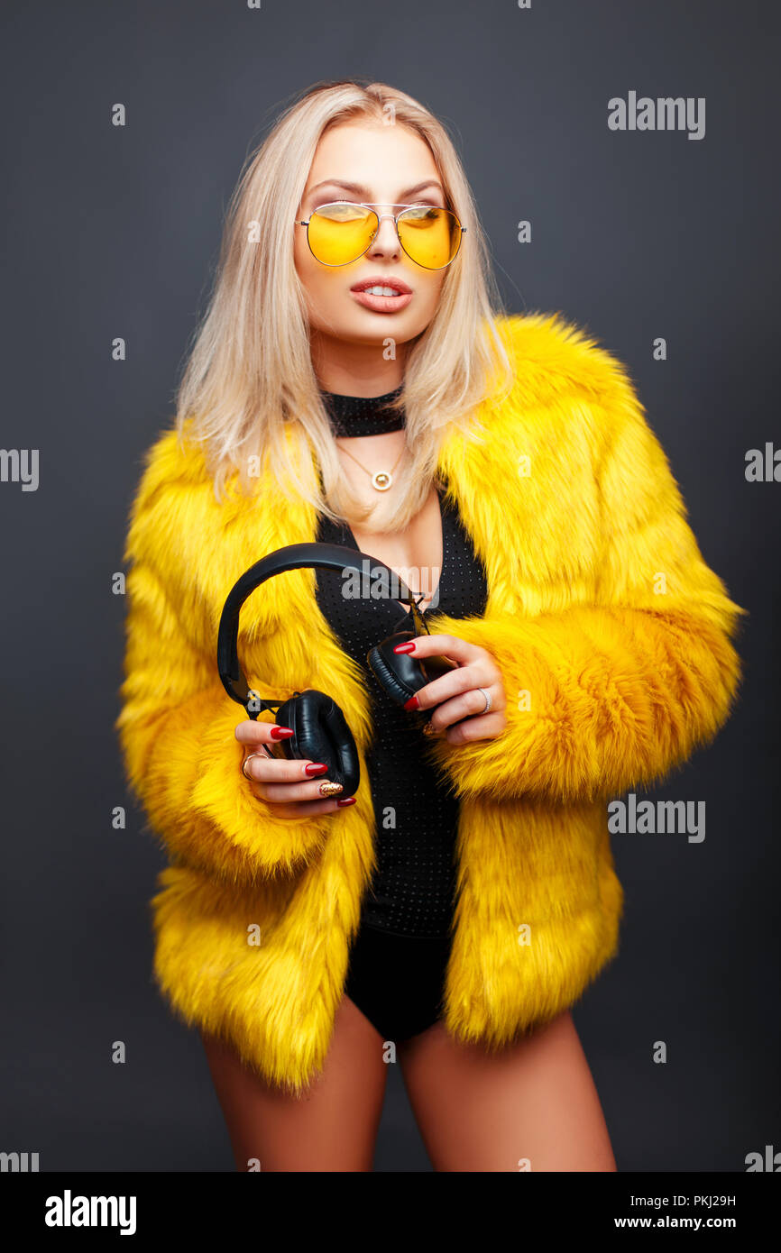 Stylish young model woman with headphones in yellow sunglasses and ...