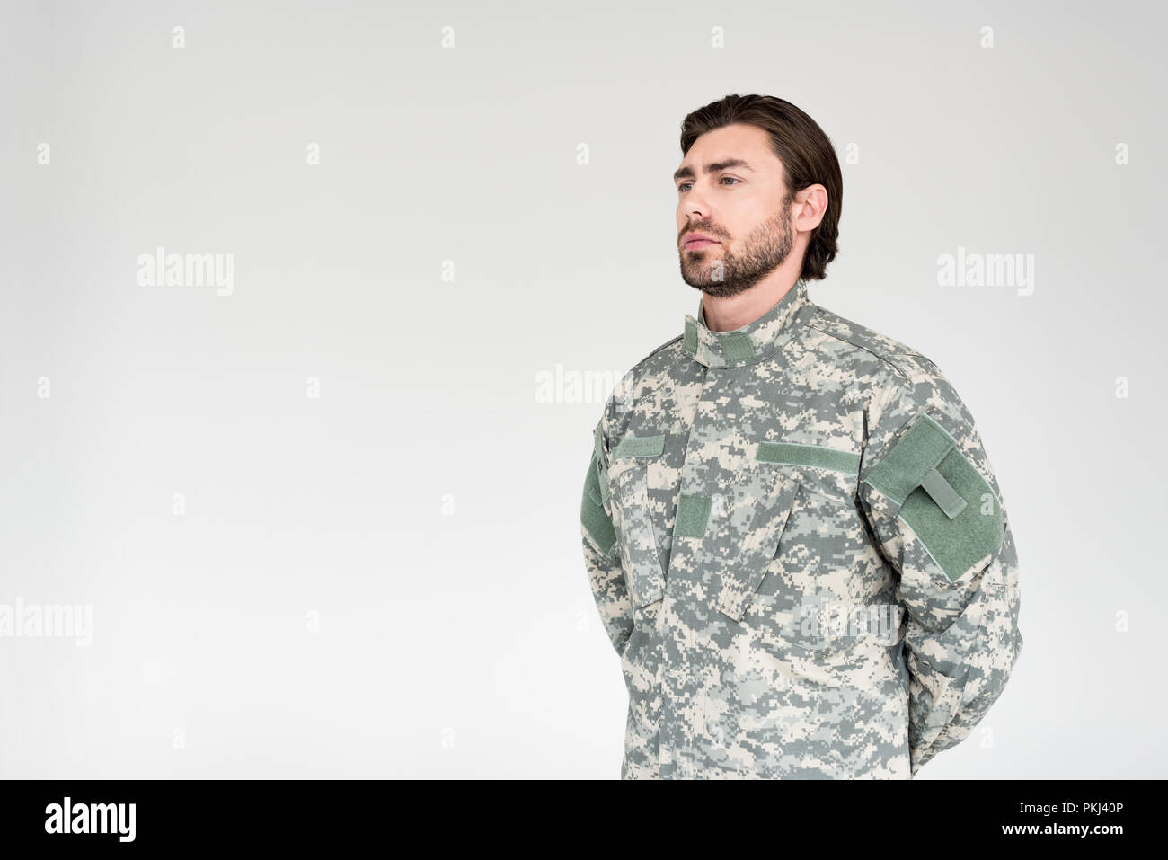 side view of confident bearded soldier in military uniform looking away ...