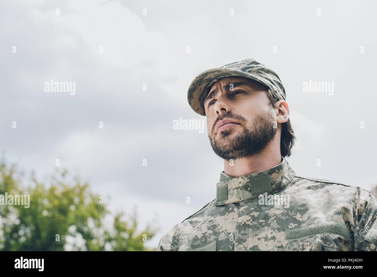 portrait of confident soldier in military uniform with cloudy sky on ...
