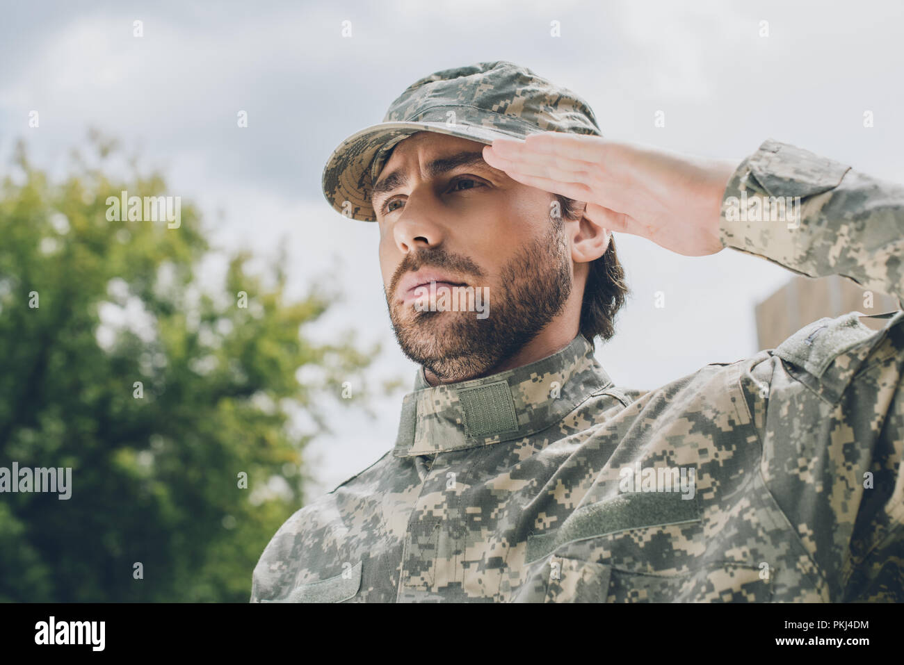 portrait of confident soldier in military uniform with cloudy sky on ...