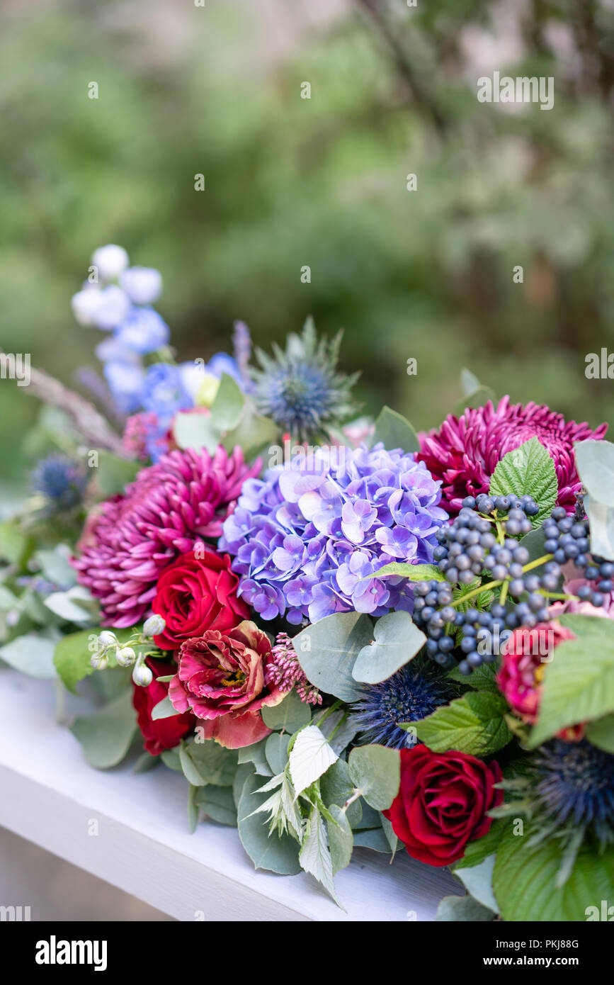 Elongated floral arrangement in vintage metal vase. table setting. Blue ...