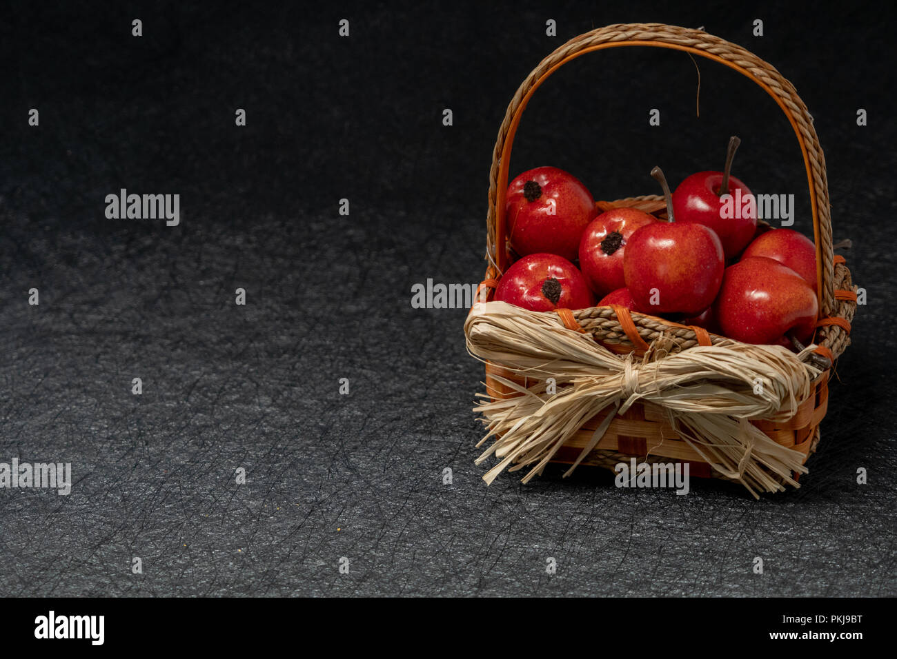 Apples in a straw basket over a black background. Fall and autumn concept Stock Photo