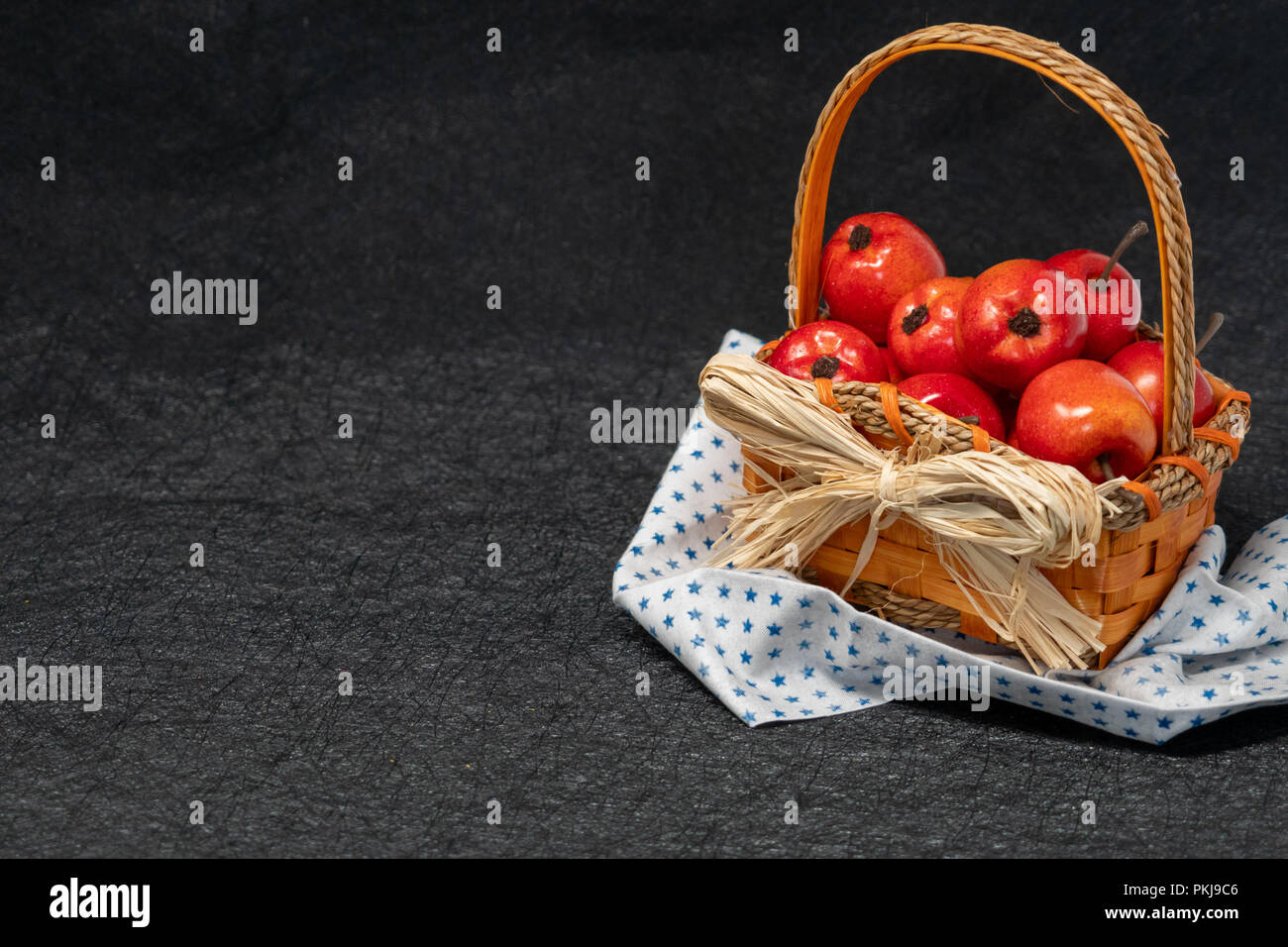 Apples in a straw basket over a black background. Fall and autumn concept, also works for Fourth of July - star napkin Stock Photo