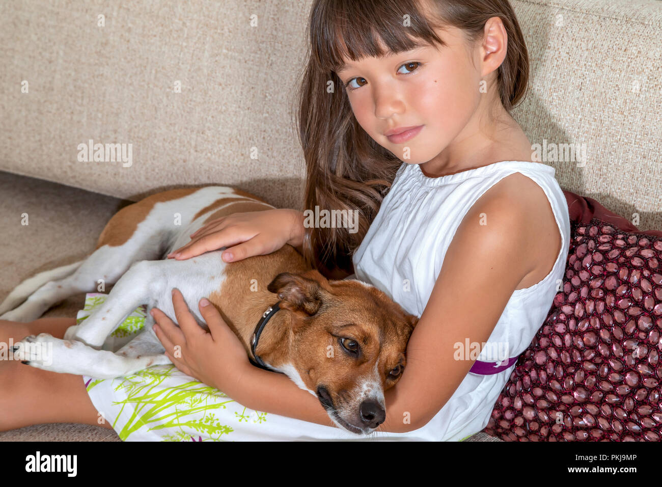 A six year old girl holding her female pet on a sofa Stock Photo