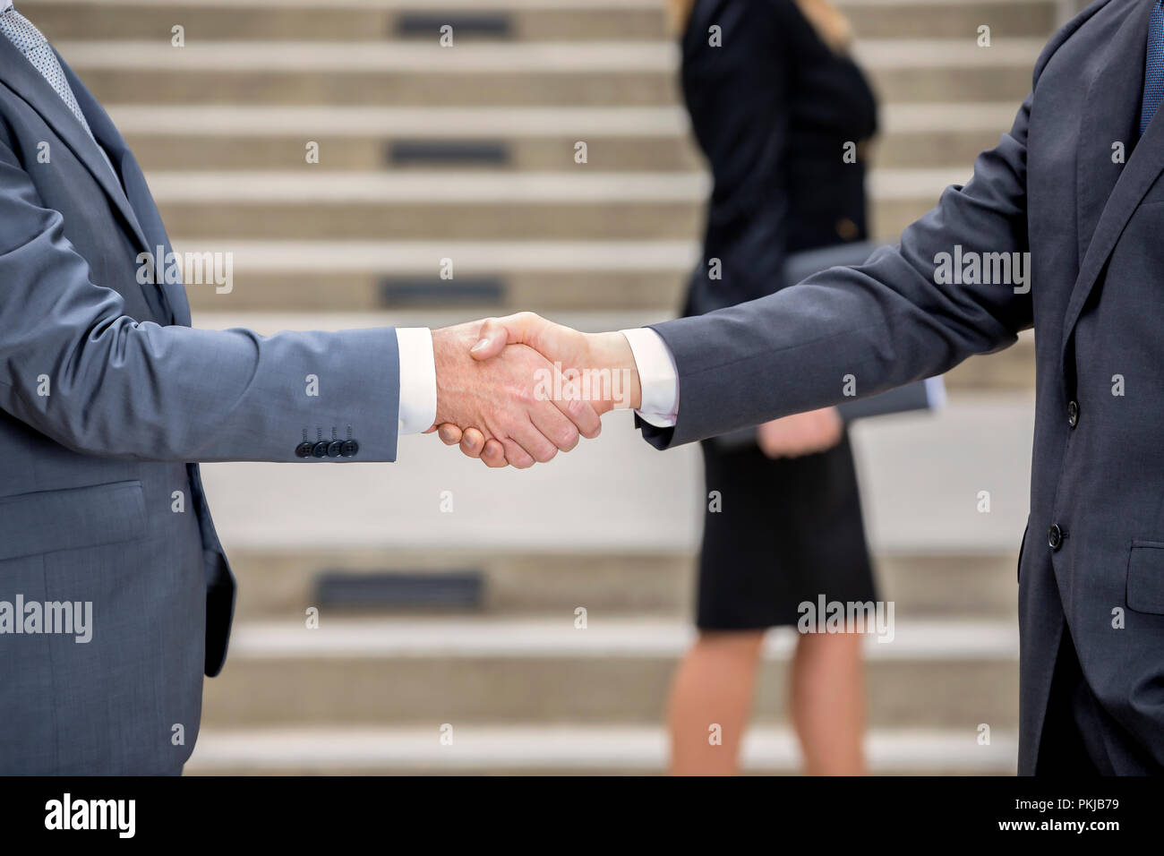Professional handshake with female colleague in the background Stock Photo