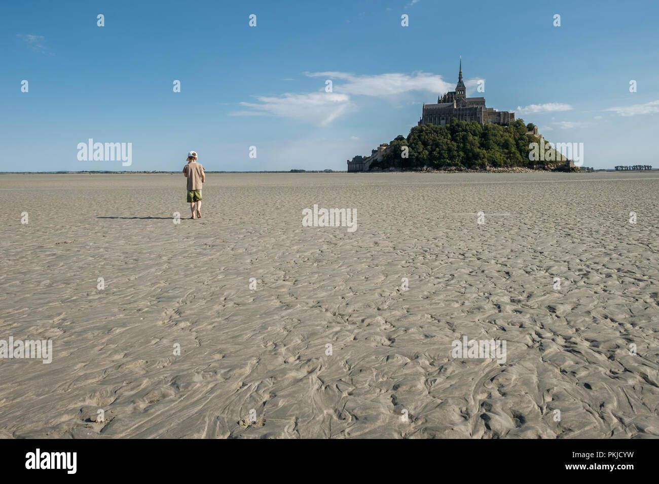 Boy walking in the bay of Mont Saint-Michel at low tide Stock Photo